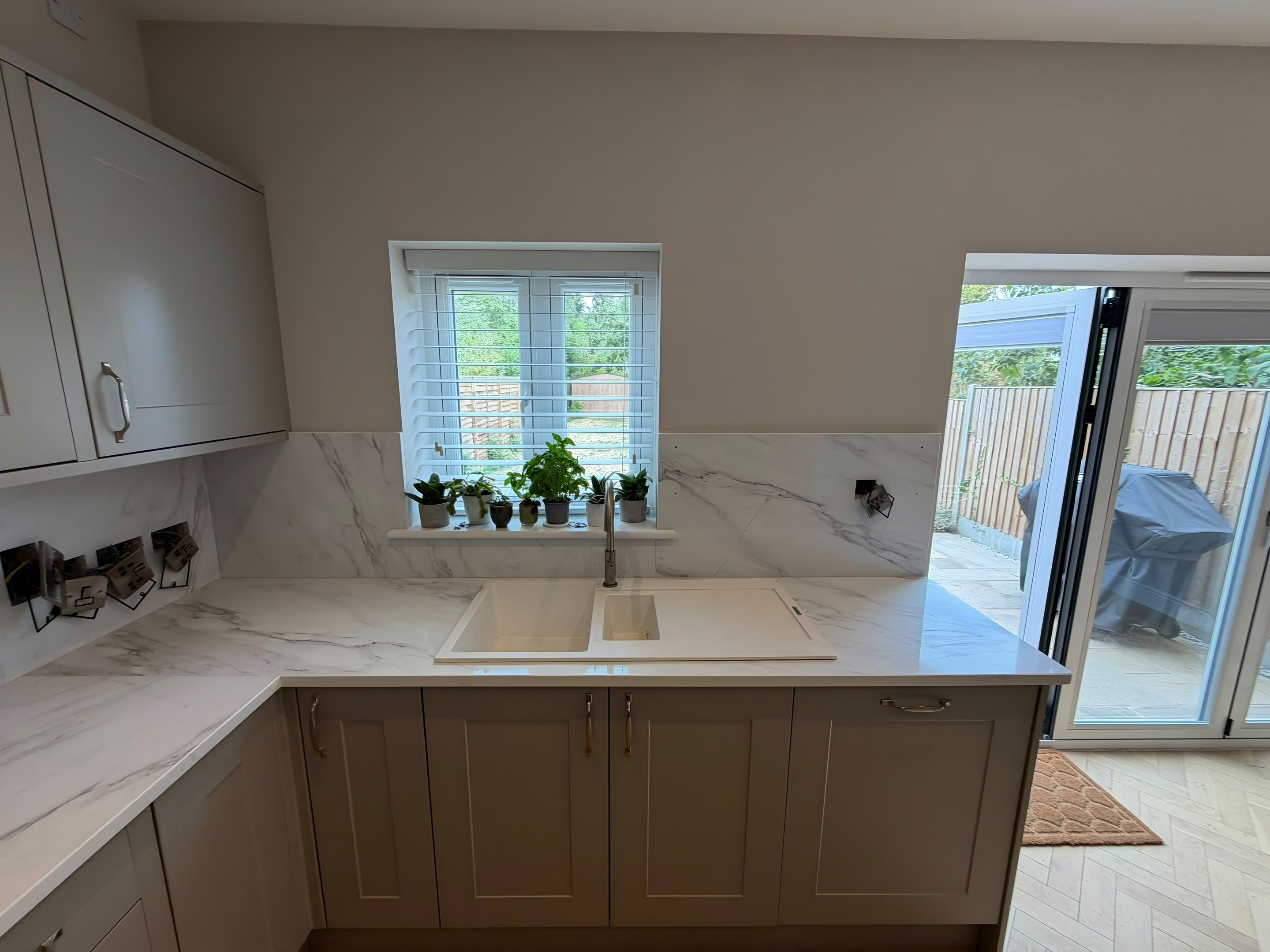 Undermount sink in a Calacatta Glacier worktop below the window, with herbs on the sill