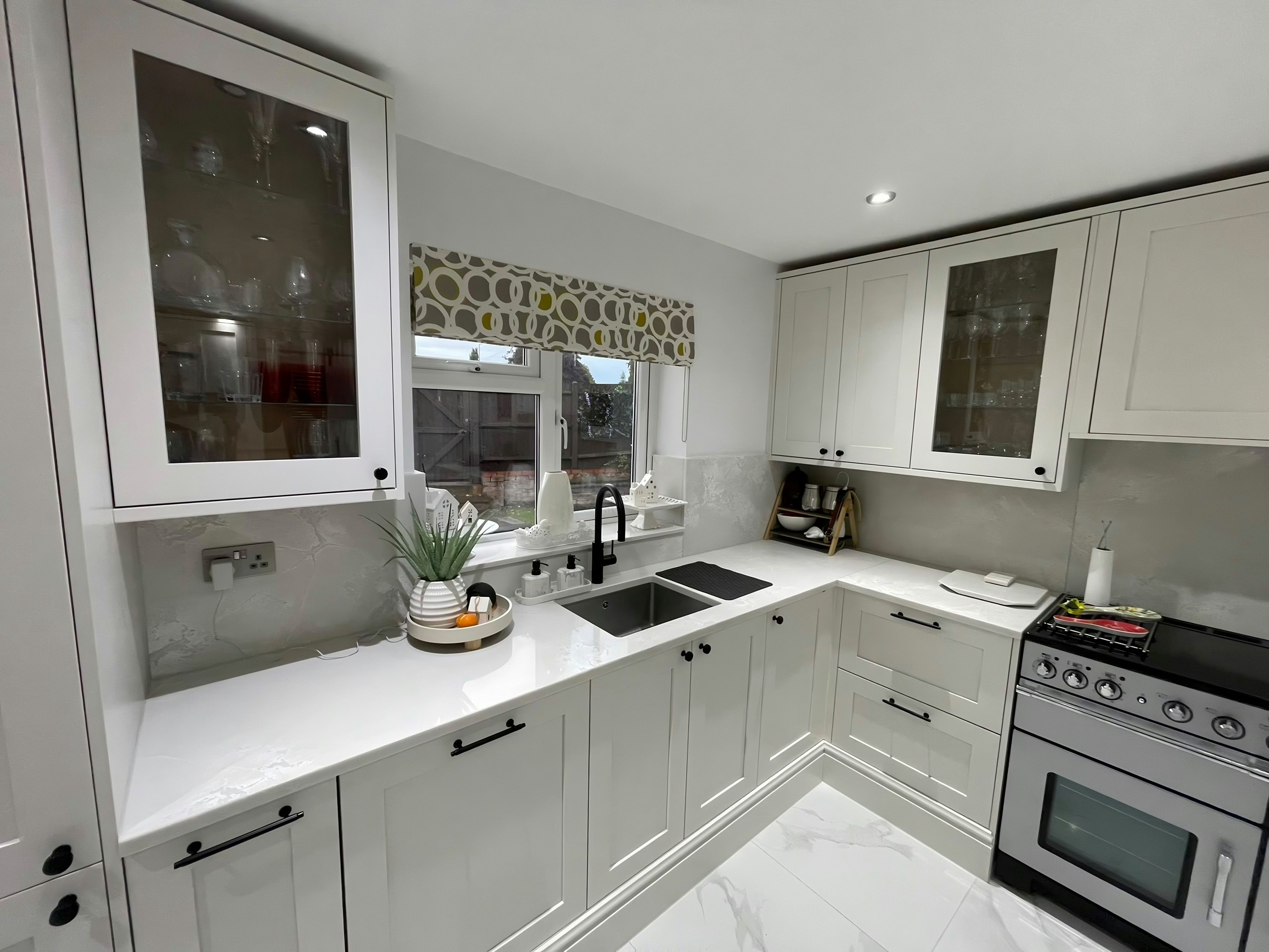 L-shaped kitchen with Polar White worktops, the sink under the window and the range cooker to the right