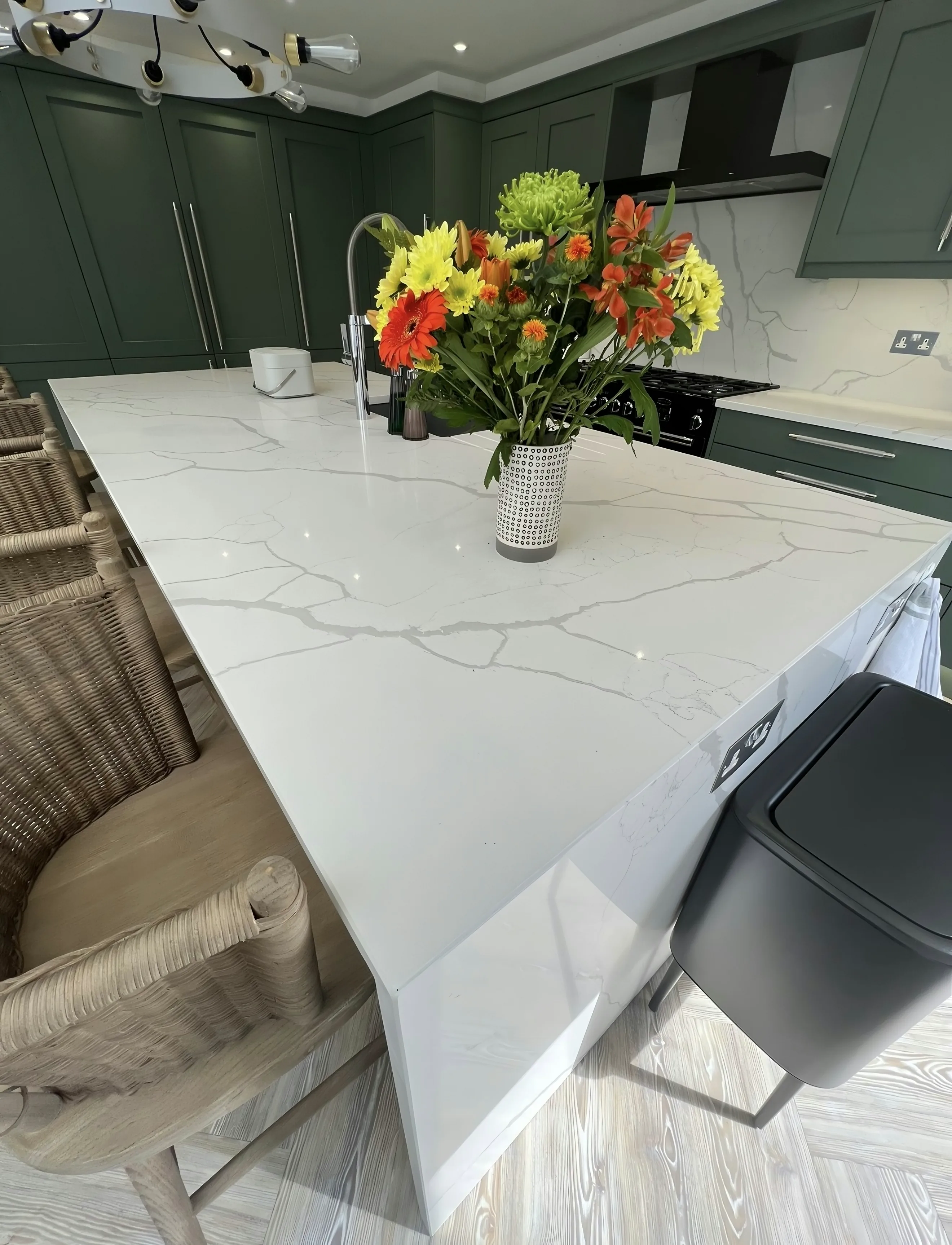 Quartz island with a waterfall end in a green shaker kitchen